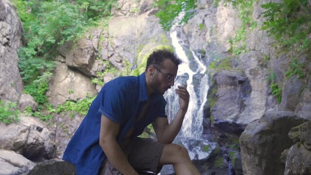 Sad man in nature.
Lonely and sad man sitting at waterfall in forest and thinking.

