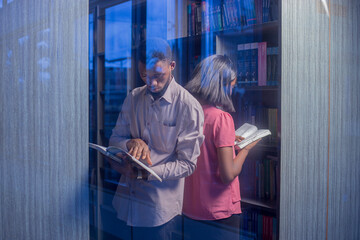 A man and woman in a library reading