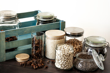 Traditional Spanish lentil stew inside a wooden bamboo bowl on a black and gray kitchen towel, fresh tomatoes, a wooden spoon and cut crystal glasses