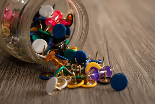 Chinches de colores derramadas sobre mesa de madera