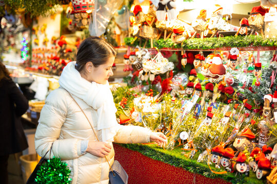 Attractive woman chooses christmas presents on outdoor Christmas market. High quality photo