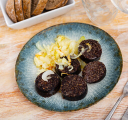 Spanish blood sausage morcilla served with grilled onion on plate