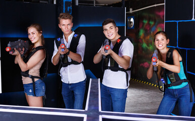 Group portrait of joyful young happy cheerful positive smiling people with laser guns in their...