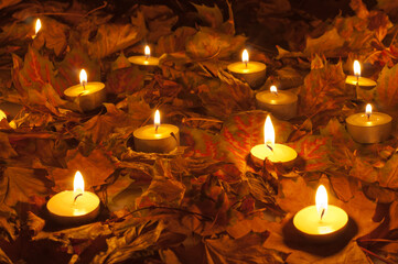 Candles burning on the autumn leaves cover at night