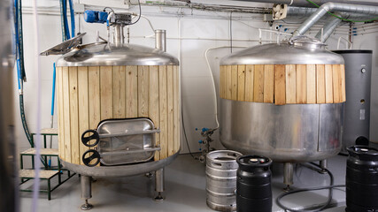 Interior of small private brewery with steel tanks trimmed with wooden planks for beer fermentation...