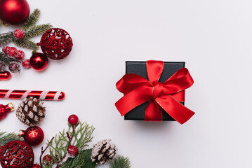 Christmas gift with a red bow on a white background with fir branches and decorations on a white background. View from above