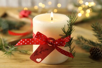 Burning candle with pinecone scent on wooden table, closeup