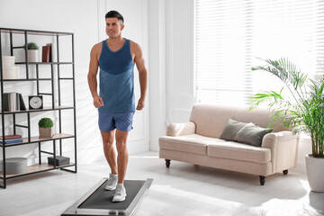 Fototapeta na wymiar Sporty man training on walking treadmill at home