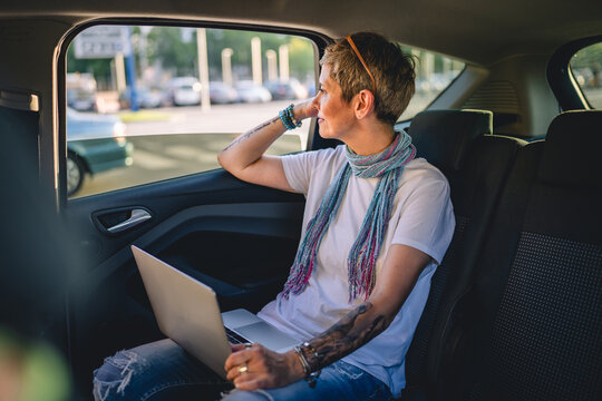 One Mature Woman Caucasian Female Sitting On The Back Seat Of The Car Working On Laptop Computer In Summer Day With Short Gray Hair Modern Manager Or Business Owner On Road Wearing Casual Copy Space