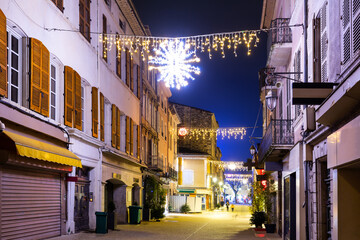 Scenic view of central street of small French town of Montelimar with bright colorful Christmas light decorations on winter twilight, Drome department