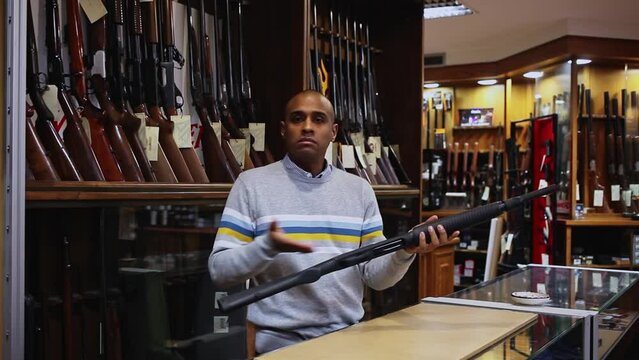 Gun shop salesman demonstrates a pump action shotgun. High quality FullHD footage