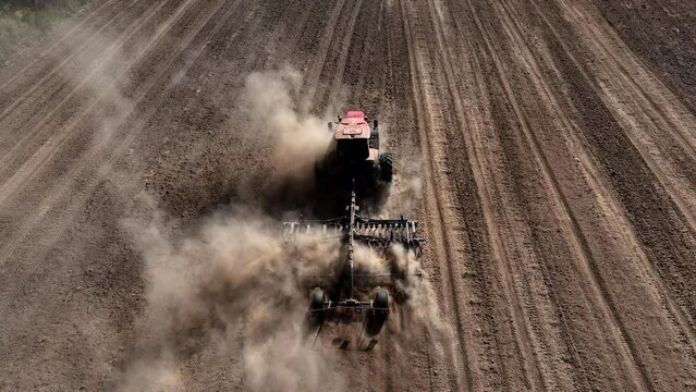 Plowing field with Tractor , drone view. Cultivated and soil tillage. Tractor with plough or plow. Agricultural tractor on cultivation field. Tractor disk harrow on ploughing field. Soil cultivation.