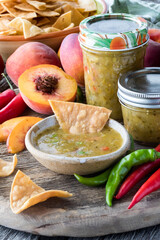 Fresh homemade jars of peach and pepper salsa with tortilla chips for dipping.