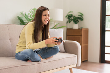 Concept of activity in home, Young woman sit on couch to control joystick while playing video game