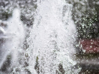 Splashes of water on dark background. Water sprays in sunny day close-up.