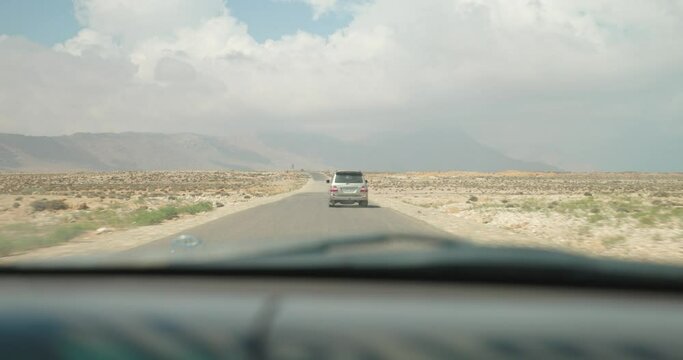 POV from a moving car to an SUV driving on an asphalt road in the middle of the desert on Socotra Island, Yemen
