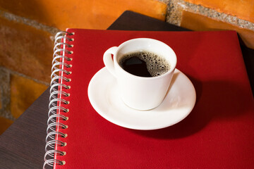 international coffee day, traditional colombian drink, coffee mug on notebooks on bedside table, top view