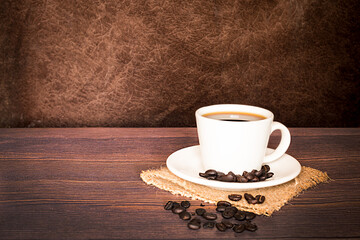 international coffee day, traditional colombian drink, cup and roasted coffee beans close-up on wooden table