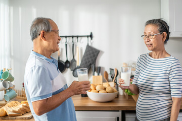 Fototapeta na wymiar Asian senior elderly couple drink a glass of milk in kitchen at home. 