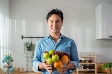 Portrait of Asian handsome male hold fruit bowl and looking at camera. 