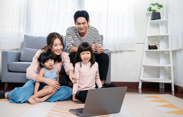 Portrait of young Asian family father mother daughter look at tablet computer lying on floor, little asian girl laptop with parents. Weekend holiday leisure time education, work from home