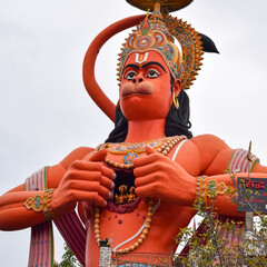 Big statue of Lord Hanuman near the delhi metro bridge situated near Karol Bagh, Delhi, India, Lord Hanuman statue touching sky - obrazy, fototapety, plakaty