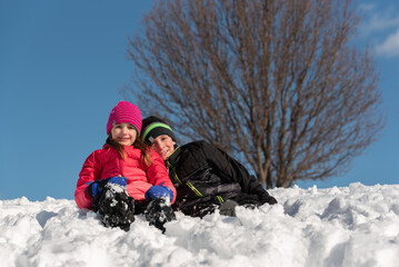 Fototapeta na wymiar brother and sister sitting in the snow on a sunny day