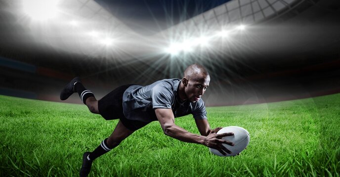 Composition of male rugby player diving holding ball on rugby pitch - Powered by Adobe