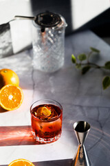 Photo of a Negroni cocktail glass with sun light and shadow and orange