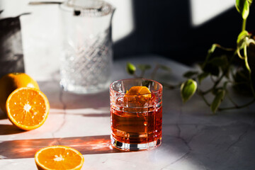 Photo of a Negroni cocktail glass with sun light and shadow and orange
