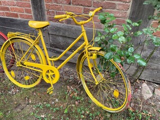Fahrrad in gelb als Dekoration lehnt an Fachwerkhaus in ländliche Umgebung