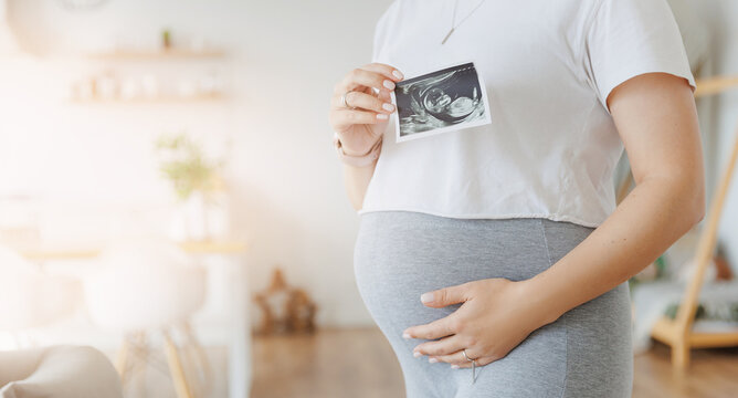 Concept banner expectant mother waiting for baby birth during pregnancy, light home background. Pregnant woman with ultrasound image