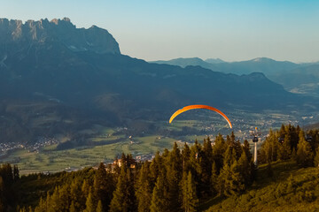Beautiful alpine summer evening view with a paraglider at the famous Hartkaiser summit, Ellmau,...