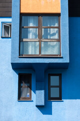 A blue-orange facade with brown windows in the sunshine