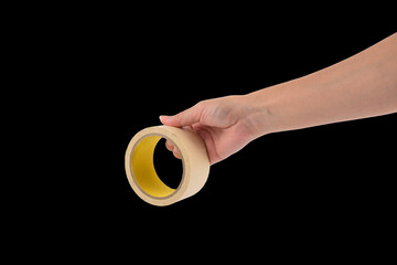 Hand holding a roll of a tape on black background.