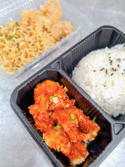 Korean sauce fried rice and fried chicken in a black box on blurred background