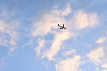 Fototapeta na wymiar Silueta de avion de pasajeros con cielo con nubes luminosas en el atardecer