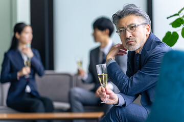 ロビーでシャンパングラスを持つシニア男性