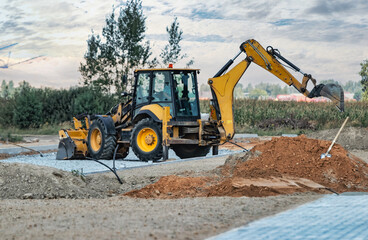 Backlit excavator on an industrial site against the background of the evening sky. Construction...