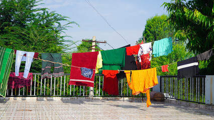 Obraz na płótnie Canvas Laundry drying on the balcony of a building. Laundry line with clothes on green tree background