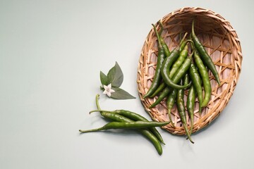 Farm fresh organic Green chili peppers. Freshly harvested healthy and spicy chilies in a basket on a green background. Copy space. 