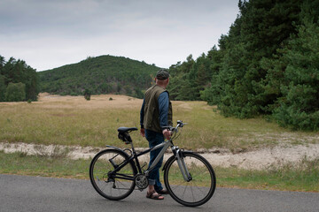 A man with bicycle on recreational cycle path looking at the hill. 