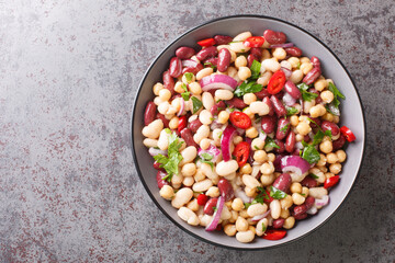 Vegetarian salad of three beans close-up in a bowl on the table. Horizontal top view from above