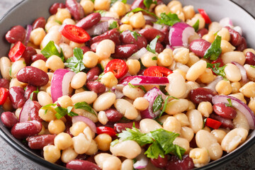 Delicious vegetable salad three beans with chili peppers and red onions close-up in a bowl on the table. Horizontal