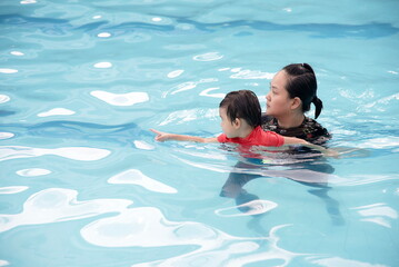 Little asian boy pointing direction for mother move in swimming pool