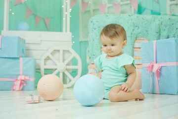 A little girl under the age of 1 year sits in the children's room