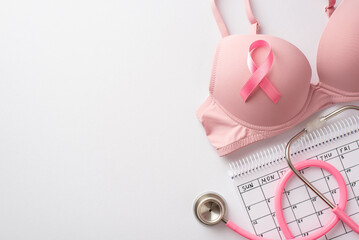 Breast cancer awareness concept. Top view photo of pink bra with pink silk ribbon stethoscope and calendar on isolated white background with empty space