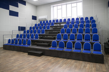 New comfortable seats for spectators on the theater stage, indoors. Blue stands. Empty seats in the stadium.