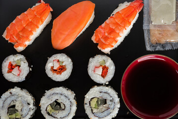 Sushi Set nigiri shrimp and salmon and sushi california rolls with avocado and maki with carrot, on wood,top view, condiments