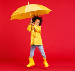 Cheerful ethnic boy jumping with umbrella